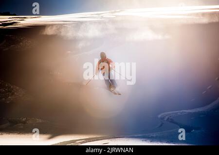 Single Off Piste Skifahrer steigt frischen Pulverschnee Piste mit Sonne hinter Stockfoto