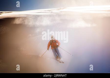 Single Off Piste Skifahrer steigt frischen Pulverschnee Piste mit Sonne hinter Stockfoto