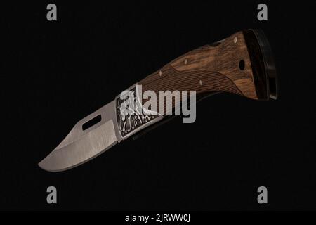 Nahaufnahme eines faltbaren handgefertigten Messers mit scharfer Klinge, Holzgriff auf schwarzem Hintergrund hergestellt in Kambodscha Stockfoto