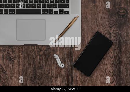 Arbeiten Sie von zu Hause aus mit einem Smartphone, Kopfhörer und einem Laptop Stockfoto