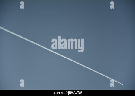 Airliner Chemtrail in großer Höhe mit weißen Kondensstreifen, am tiefblauen Himmel Stockfoto