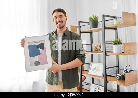 Mann, der das Haus mit Bild im Rahmen schmückt Stockfoto