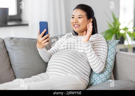 Glückliche Schwangere, die einen Videoanruf am Telefon hat Stockfoto