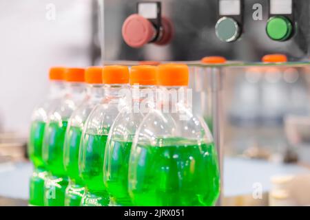 Reihe von PET-Flaschen mit grüner Limonade auf dem Förderband - Nahaufnahme Stockfoto