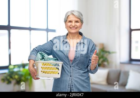 Lächelnde ältere Frau mit Wäschekorb Stockfoto