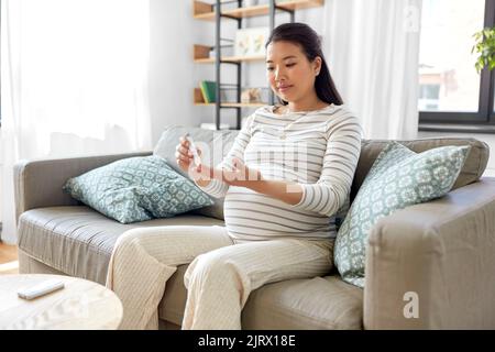 Schwanger Frau mit Glukosimeter macht Bluttest Stockfoto