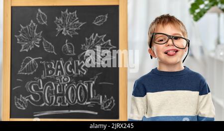 Kleiner Student Junge in Brille zeigt Zunge Stockfoto