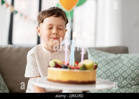 Kleiner Junge mit Geburtstagstorte machen Wunsch Stockfoto