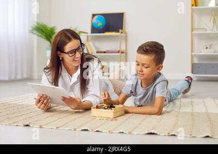 Glücklicher Junge, der Spaß hat, während er mit einem professionellen Logopädin Briefe lernt Stockfoto