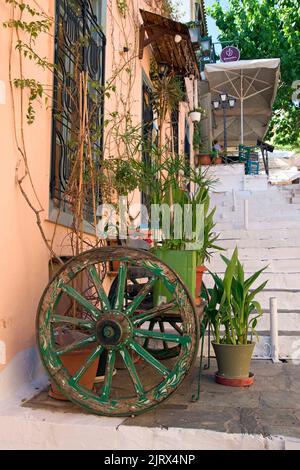 Altes Kutschenrad und Blumentöpfe in der Gegend von Plaka in Athen, Griechenland Stockfoto