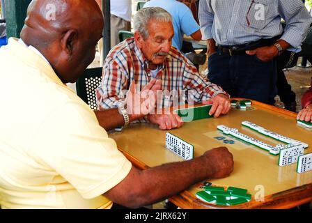 Eine Gruppe älterer Männer genießt es, sich im kubanischen Viertel Calle Ocho in Miami, Florida, mit anderen zu treffen und Dominos zu spielen Stockfoto