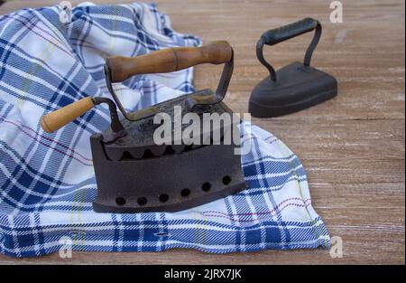 Bild von alten, kohlebefeuerten Eisen mit einem zu bügelenden Hemd. Alte Erinnerungen und Bräuche Stockfoto