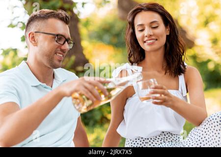 Glückliches Paar mit Wein beim Picknick im Park Stockfoto