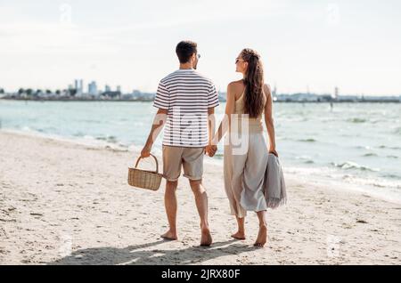 Glückliches Paar mit Picknickkorb beim Strandspaziergängen Stockfoto