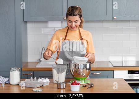 Glückliche junge Frau, die zu Hause in der Küche kocht Stockfoto