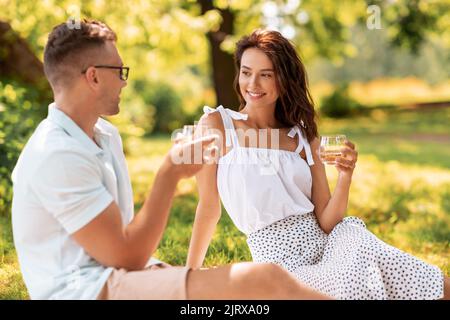 Ein glückliches Paar, das im Sommerpark Getränke toaste Stockfoto