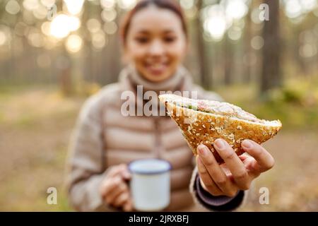 Frau trinkt Tee mit Sandwich im Herbstwald Stockfoto