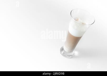 Mehrschichtiger Kaffee in einem transparenten, schrägen Glas auf weißem Hintergrund Stockfoto