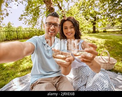 Ein Paar trinkt Wein und nimmt Selfie im Park Stockfoto