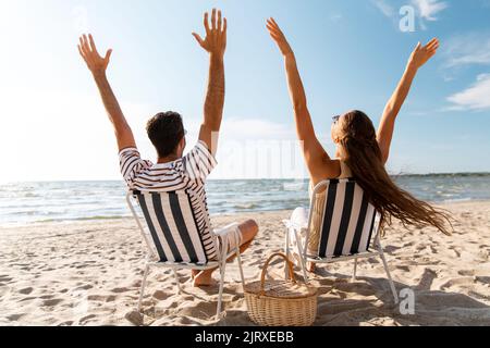 Glückliches Paar, das in Klappstühlen am Strand sitzt Stockfoto