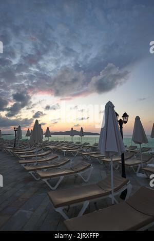 Sonnenliegen und Sonnenschirme auf dem Dach eines Hotels in Chania Kreta - Griechenland bei Sonnenuntergang Stockfoto