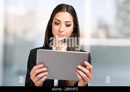 Frau, die an einem Remote-Meeting mit einem Tablet und teilnimmt Headset Stockfoto