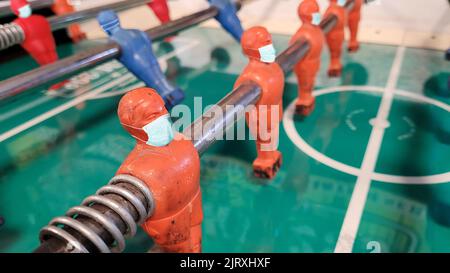 Konzeptionelles Covid-Bild: Tischfußballspieler trägt Masken zum Schutz vor einer Coronavirus Covid 19-Pandemie Stockfoto