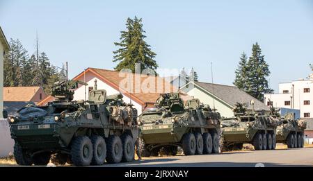 Stryker gepanzerte Fahrzeuge von 3. Platoon, Blackhorse Company, 2-3 Infantry Regiment, 1-2 Stryker Brigade Combat Team vor der Rückkehr zum Kontrollzentrum nach einer Bewegung-zu-Kontakt-städtischen Razzia Übung auf Joint Base Lewis-McChord, Washington, 24. August 2022. Die Übung war Teil einer zweitägigen Demonstrationsveranstaltung, die vom Program Executive Office of Ground Combat Systems veranstaltet wurde, mit dem Ziel, das Feedback der Soldaten in die Entwicklung neuer militärischer Kampftechnologien zu integrieren. (USA Armee-Foto von SPC. Chandler Coats, 5. Mobile Public Affairs Detachment) Stockfoto