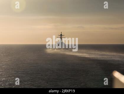 220825-N-EL850-1521 STRASSE VON GIBRALTAR (AUG 25, 2022) der Arleigh Burke-Klasse Lenkraketen-Zerstörer USS Farragut (DDG 99) segelt in den Sonnenaufgang, während er am 25. August 2022 die Straße von Gibraltar ins Mittelmeer überführt. The George H.W. Die Bush Carrier Strike Group (CSG) besteht aus George H.W. Bush, Carrier Air Wing (CVW) 7, Destroyer Squadron (DESRON) 26, der Information Warfare Commander und der Ticonderoga-Klasse-Lenkflugkörper-Kreuzer USS Leyte Gulf (CG 55). The George H.W. Die Bush Carrier Strike Group befindet sich im geplanten Einsatzgebiet der US Naval Forces Europe Stockfoto