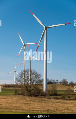 Gruppe von Windenergieanlagen vor einem strahlend blauen Himmel in einer ländlichen Landschaft, geeignet als symbolisches Bild für erneuerbare Energien Stockfoto