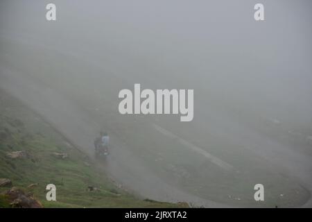 Srinagar, Kaschmir, Indien. 26. August 2022. Ein Motorradfahrer fährt bei nebligen Wetterbedingungen am Stadtrand von Srinagar durch eine Straße. Leichte bis mäßige Regenfälle setzten sich fort, Kaschmir zu schlagen, und die Meteorologische Abteilung hat ziemlich weit verbreitete leichte bis mäßige Regenschauer in den nächsten 24 Stunden vorhergesagt. (Bild: © Saqib Majeed/SOPA Images via ZUMA Press Wire) Bild: ZUMA Press, Inc./Alamy Live News Stockfoto