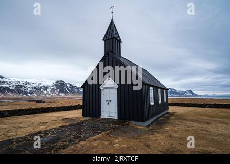 Spätwinter-Landschaft an der malerischen schwarzen Kirche von Búðir (oder Budir), mit den Bergen der Halbinsel Snæfellsnes im Hintergrund, Island Stockfoto