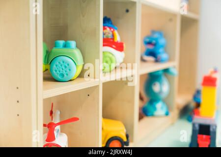 Verschiedene Arten von bunten Kunststoff- und Plüschspielzeug auf den Regalen im Spielzimmer der Kindergartenschule. Spielerisch lernen. Hochwertige Fotos Stockfoto