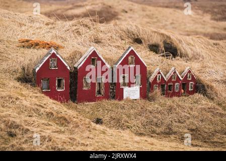 Vollbildaufnahme des winzigen roten Holzhauses im Gras in der Nähe der Strandarkirkja-Kirche, Selvogur, Halbinsel Reykjanes, Island Stockfoto