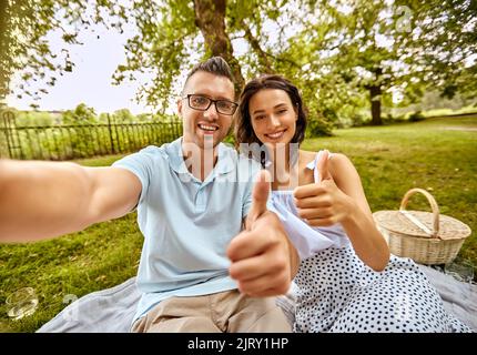 Ein Paar nimmt Selfie und zeigt Daumen nach oben im Park Stockfoto