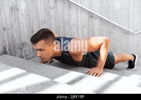 Junger Mann macht Liegestütze auf Treppen im Freien Stockfoto