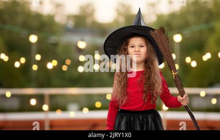 Mädchen in schwarzem Hexenhut mit Besen an halloween Stockfoto