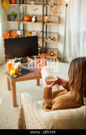 Frau schaut an halloween Fernsehen und trinkt Kakao Stockfoto