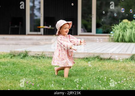 Happy Baby Mädchen spielen mit Seifenblasen im Freien Stockfoto