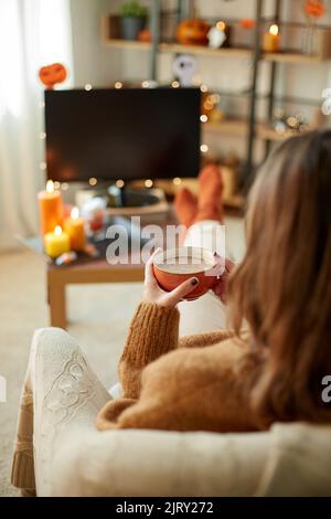 Frau schaut an halloween Fernsehen und trinkt Kakao Stockfoto