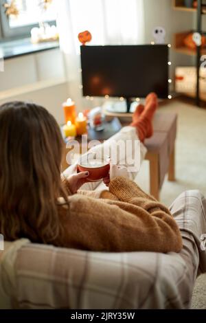 Frau schaut an halloween Fernsehen und trinkt Kakao Stockfoto