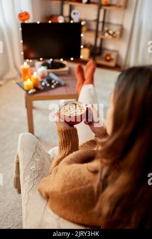 Frau schaut an halloween Fernsehen und trinkt Kakao Stockfoto