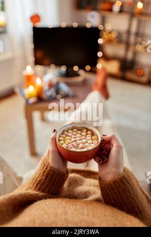 Frau schaut an halloween Fernsehen und trinkt Kakao Stockfoto