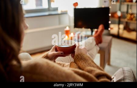 Frau schaut an halloween Fernsehen und trinkt Kakao Stockfoto