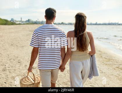 Glückliches Paar mit Picknickkorb beim Strandspaziergängen Stockfoto