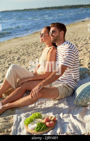 Glückliches Paar beim Picknick am Sommerstrand Stockfoto