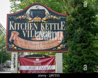 Ein Straßenschild, das über das Kitchen Kettle Village an einem sonnigen Tag erzählt Stockfoto