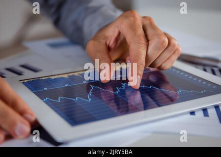 Nahaufnahme der Geschäftsmänner Hand, die die Grafik auf dem digitalen Tablet analysieren Stockfoto