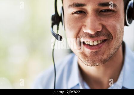 Ich danke Ihnen für Ihren Anruf. Porträt eines glücklichen jungen Telemarketers bei der Arbeit. Stockfoto