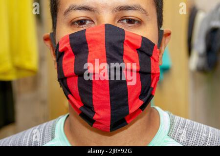 Schwarze Männer Masken in roten und schwarzen Farben zum Schutz gegen Coronavirus in Rio de Janeiro Brasilien hausgemacht. Stockfoto